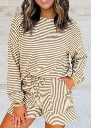 Woman wearing a striped long-sleeve top and shorts set against a light gray background