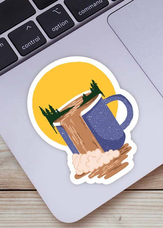 Sticker of a coffee mug with trees and a sunset on a laptop