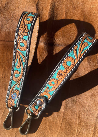 Decorative leather strap with turquoise and brown patterns on a wooden surface