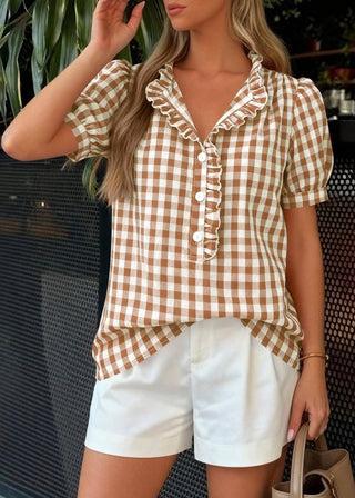 Woman wearing a checkered top and white shorts outdoors.
