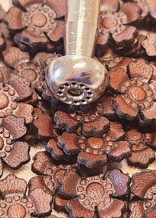 Decorative metal flower stamp on a bed of similar stamps