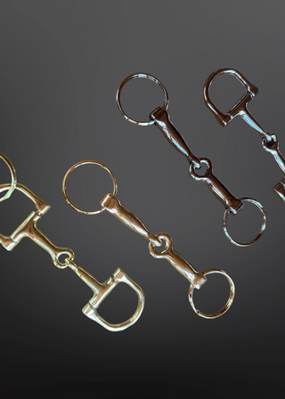 Two pairs of horse bit equipment on a dark background