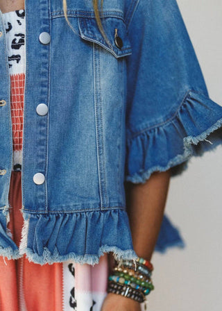 Close-up of a person wearing a blue denim jacket with ruffled edges.