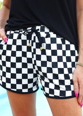Person wearing black and white checkered shorts with a blurred background