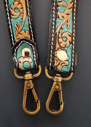 Pair of leather straps with intricate designs on a dark background