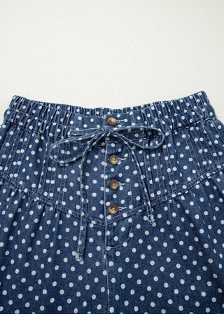Blue denim pants with white polka dots and button details on a light gray background