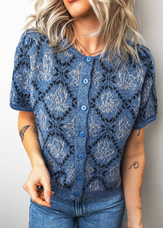 Woman wearing a blue patterned cardigan against a plain background