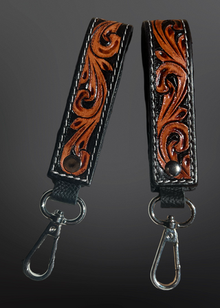 Pair of leather straps with intricate designs on a dark background