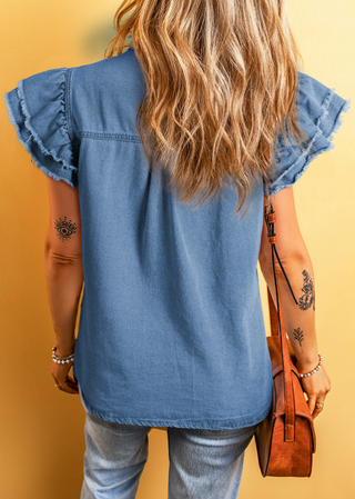 Person wearing a blue denim shirt with ruffled sleeves against a yellow background