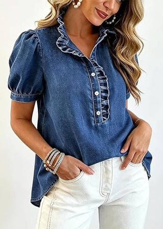 Woman wearing a blue denim shirt with ruffled collar and white pants on a white background
