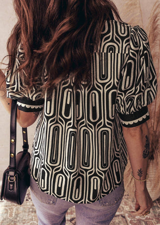 Person wearing a black and white patterned shirt with a blurred background