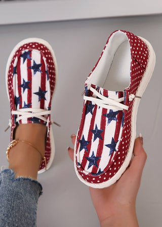 Casual canvas shoes with a patriotic stars, stripes, and polka dot design, shown with one shoe worn with jeans and a gold anklet and the other held in hand.