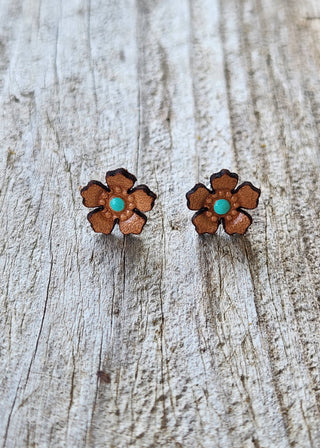 Flower-shaped earrings with turquoise centers on a wooden surface
