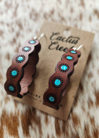 Wooden earrings with turquoise stones on a 'Cactus Creek' branded card against a fur background