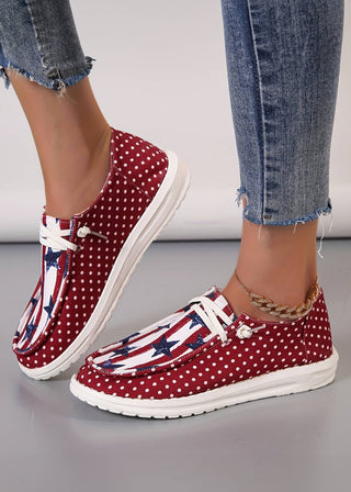 Casual canvas shoes with a patriotic stars, stripes, and polka dot design, shown worn with jeans and a gold anklet.