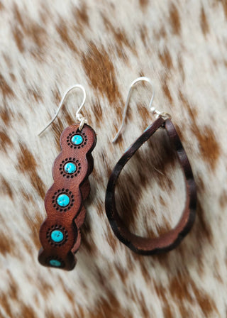 Pair of brown leather earrings with turquoise stones on a fur background
