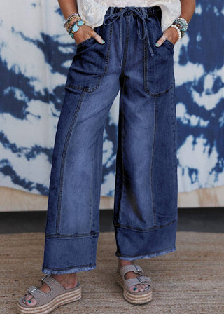 Person wearing wide-leg jeans with a tie-dye wall in the background