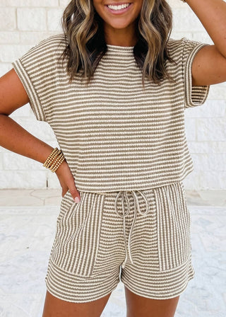 Woman wearing a beige and white striped romper against a light background