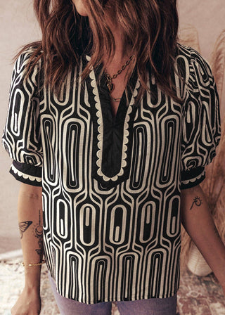Person wearing a black and white patterned shirt with tattoos visible on arms.