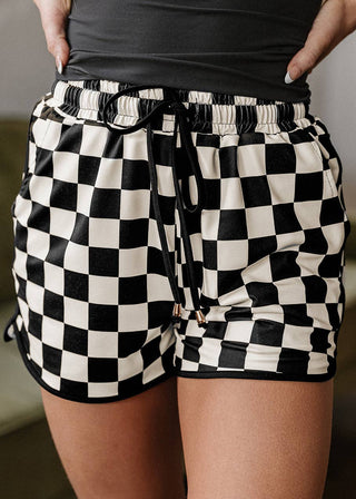 Person wearing black and white checkered shorts with a blurred background