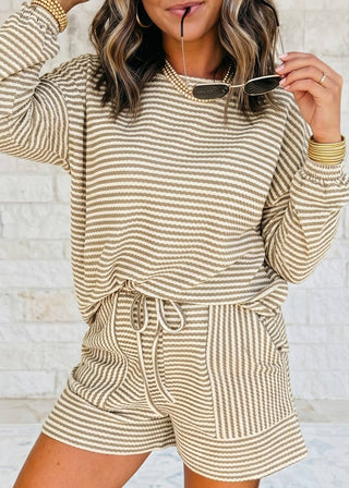 Woman wearing a beige and white striped loungewear set with sunglasses.