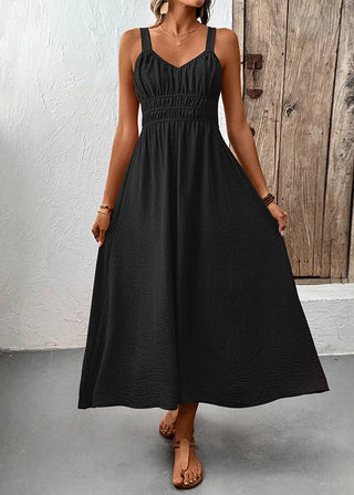 Woman wearing a black dress standing in front of a wooden door.