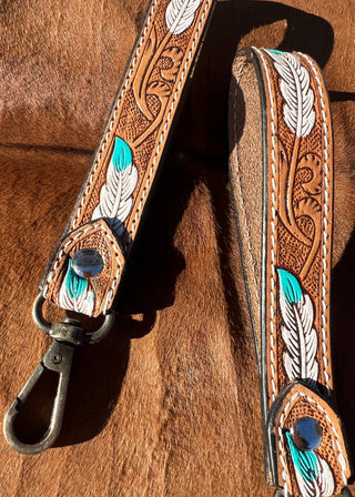 Brown leather strap with intricate designs and a metal clasp on a brown leather background