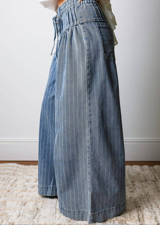 Person wearing a pair of wide-leg denim pants on a light background