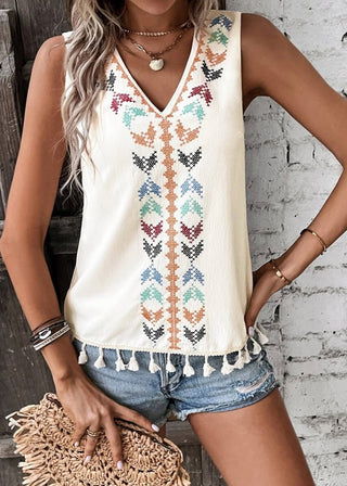 Woman wearing a sleeveless top with butterfly pattern and denim shorts against a rustic wooden and brick wall.