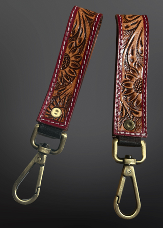 Two leather keychains with floral patterns on a dark gray background