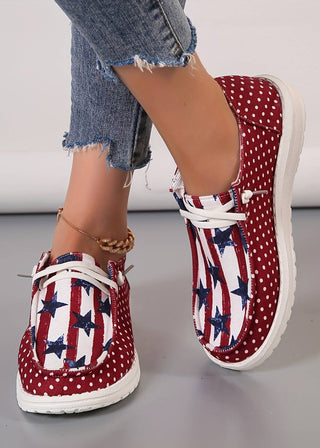Casual canvas shoes with a patriotic stars, stripes, and polka dot design, shown worn with jeans and a gold anklet.