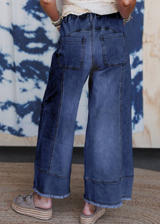 Person wearing wide-leg jeans with a tie-dye curtain in the background