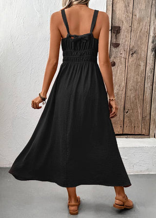 Woman wearing a black dress standing in a room with a wooden door.
