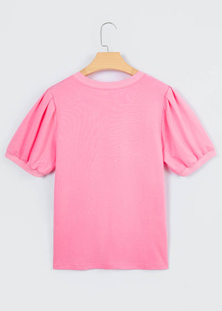 Pink blouse with puff sleeves on a wooden hanger against a white background