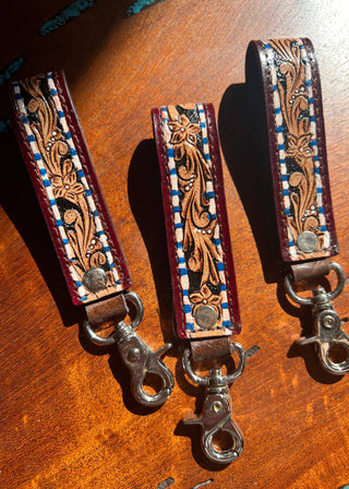 Two leather straps with intricate designs on a wooden surface