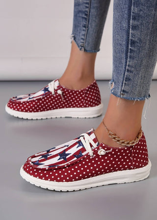 Casual canvas shoes with a patriotic stars, stripes, and polka dot design, shown worn with jeans and a gold anklet.