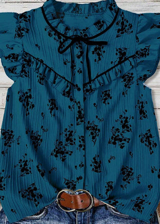 Blue floral blouse with ruffled sleeves on a wooden surface