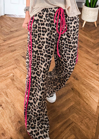 Leopard print pants with pink drawstring on a wooden floor