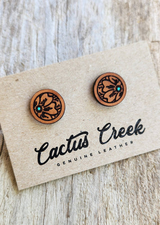 Pair of leather earrings on a Cactus Creek branded card against a wooden background