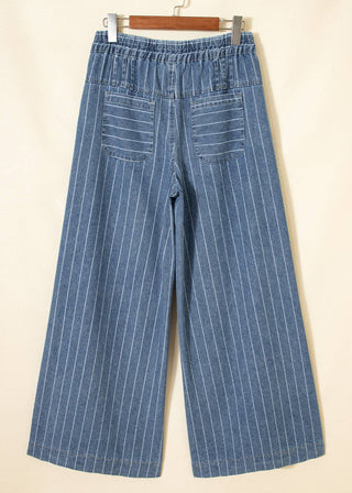 Blue pinstripe pants hanging on a wooden hanger against a beige background