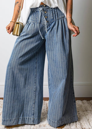 Person wearing blue striped wide-leg jeans with a white top against a neutral background