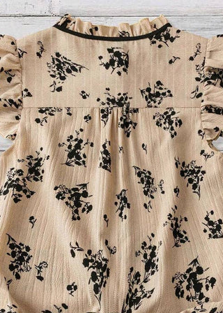 A beige sleeveless blouse with black floral print and ruffled shoulders.