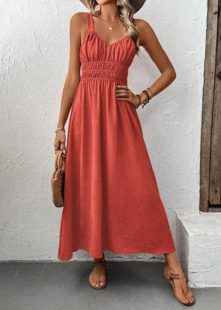 Woman wearing a red dress standing against a white wall with a wooden door.