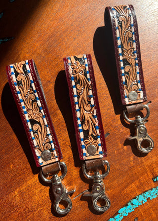 Two leather straps with intricate designs on a wooden surface