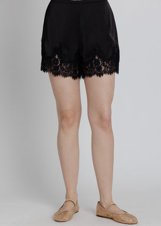 Black lace shorts worn by a person on a gray background