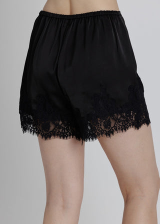 Black lace-trimmed satin shorts on a neutral background