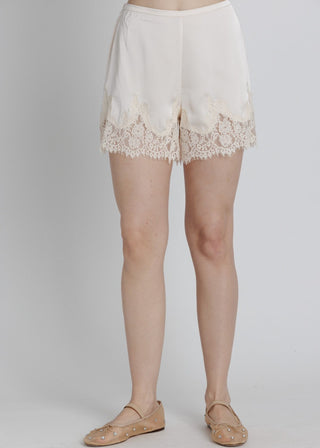 White lace shorts worn by a person on a plain background