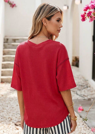 Woman wearing a red ribbed top with bold white “USA” lettering and red stitching