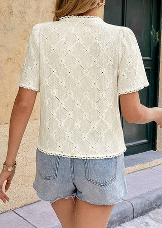 Person wearing a white lace top and denim shorts walking outdoors.