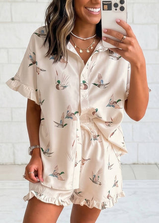 Woman wearing a beige pajama set with duck print, taking a selfie.